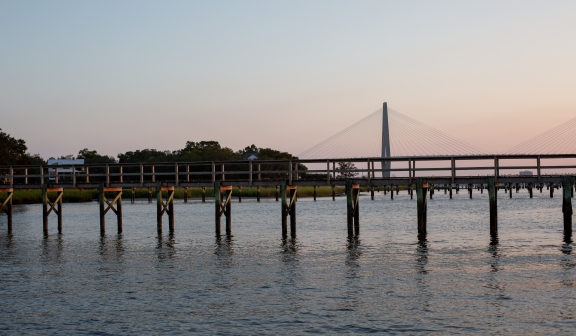 A wooden bridge on water next to the Ravenel Jr. Bridge