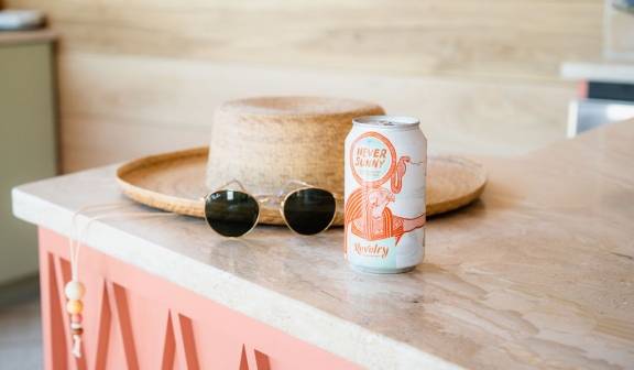 A straw hat sunglass and soda can placed on top of a cabinet