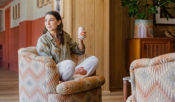 A woman sitting on a sofa chair and holding a soda can in her hand