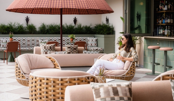 Side shot of a woman sitting on the patio chair with a drink in her hand