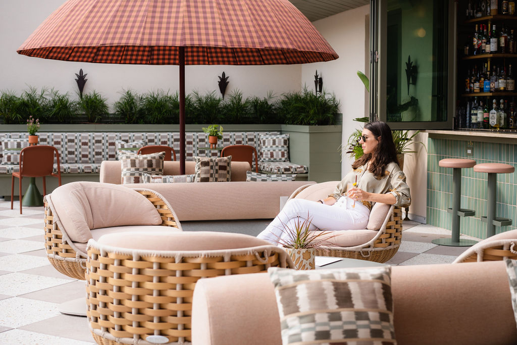 Side shot of a woman sitting on the patio chair with a drink in her hand