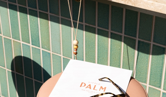 A menu for Little Palm on a stool with sunglasses