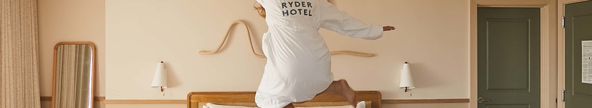 A woman in a bathrobe jumping on the bed