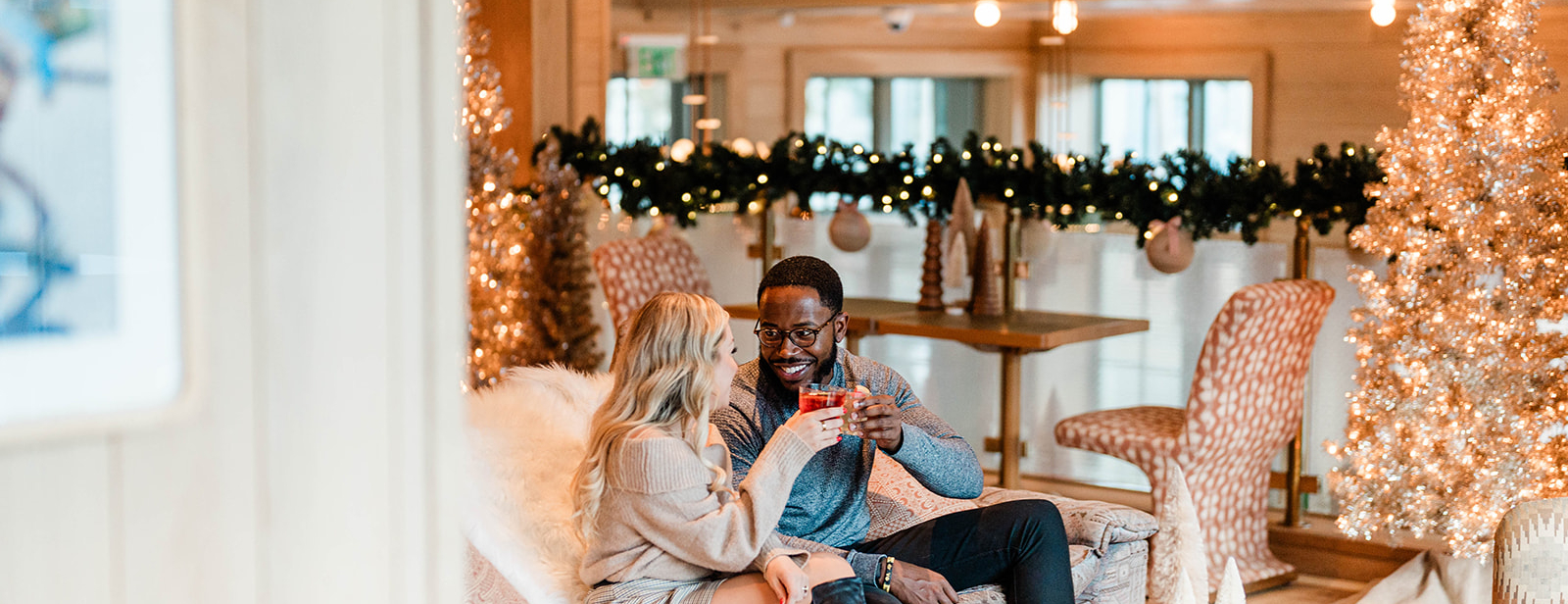 Couple sitting on couch in Christmas Mezzanine cheering drinks