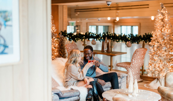 Couple sitting on couch in Christmas Mezzanine cheering drinks