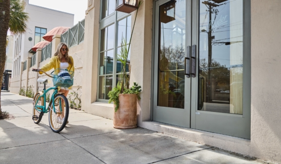 Woman walking bike up to hotel front door