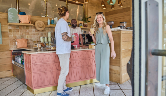 woman and man standing in front of coffee bar holding beverages