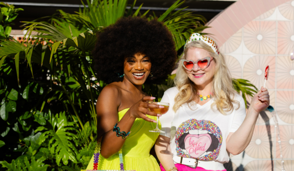 two women in vibrant clothes holding up drinks