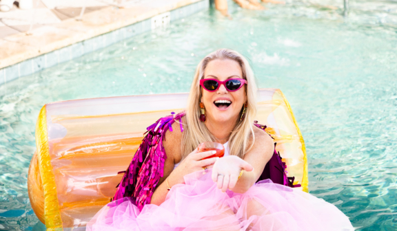 woman in vibrant clothes near pool holding a drink
