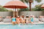 five women with legs in the water poolside