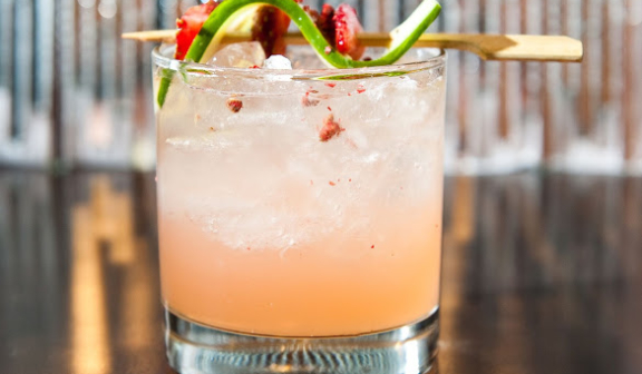 peach colored cocktail with twist of lime