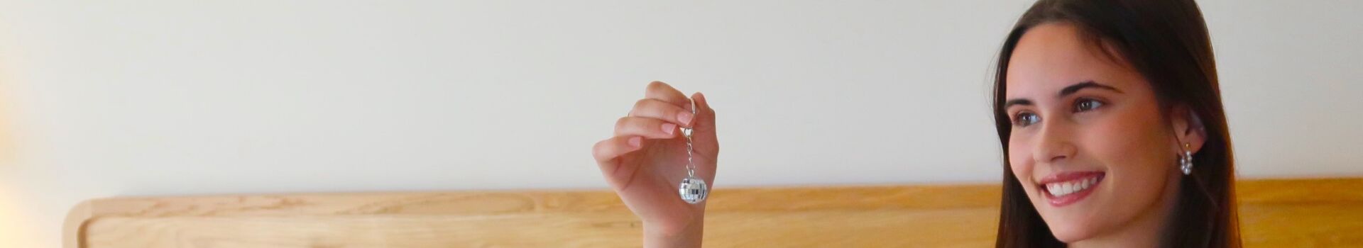Women on bed in guest room in white PJs holding a disco ball keychain