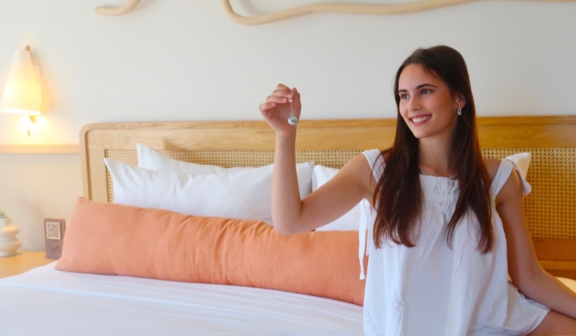 Women on bed in guest room in white PJs holding a disco ball keychain