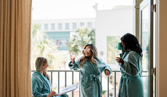 three girls standing on balcony in green robes